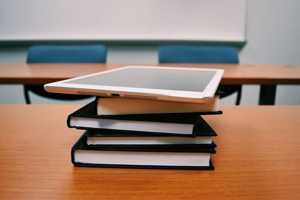 Silver Ipad on Stack of Books on desk in classroom