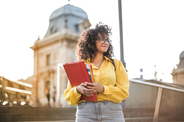 college student In Yellow Jacket Holding Books on campus